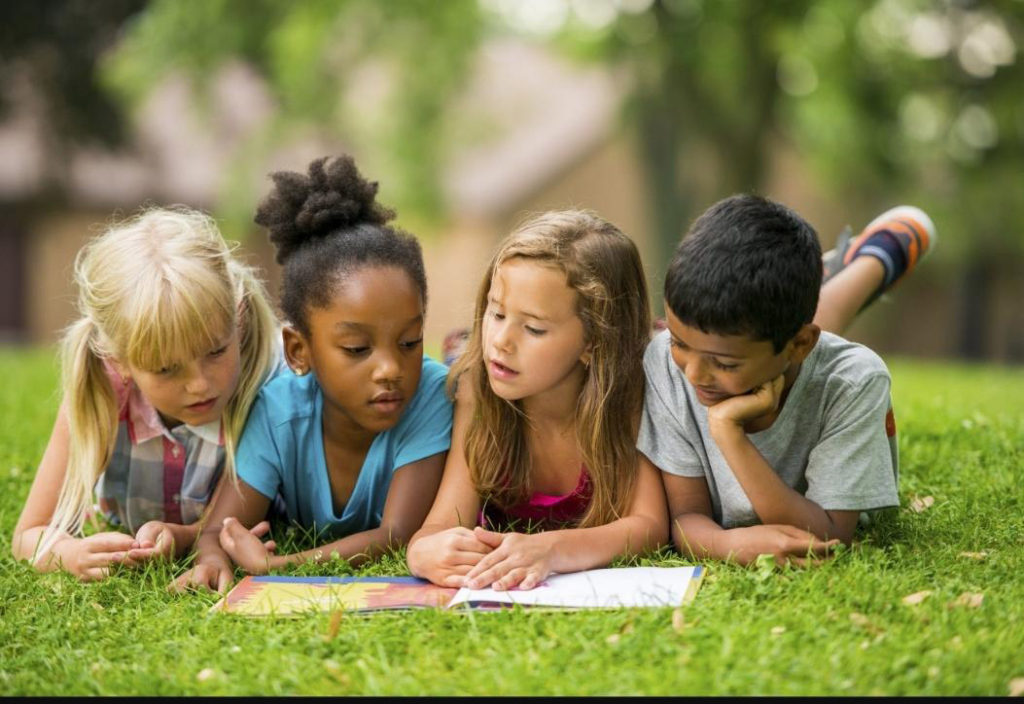 Kids lying in the grass while reading
